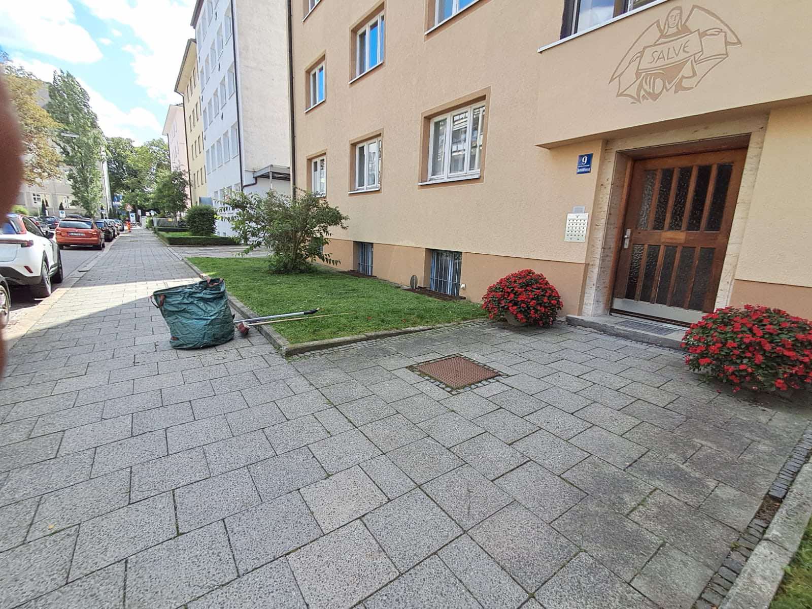 Gepflegte Grünfläche und gereinigter Eingangsbereich eines Münchner Wohnhauses