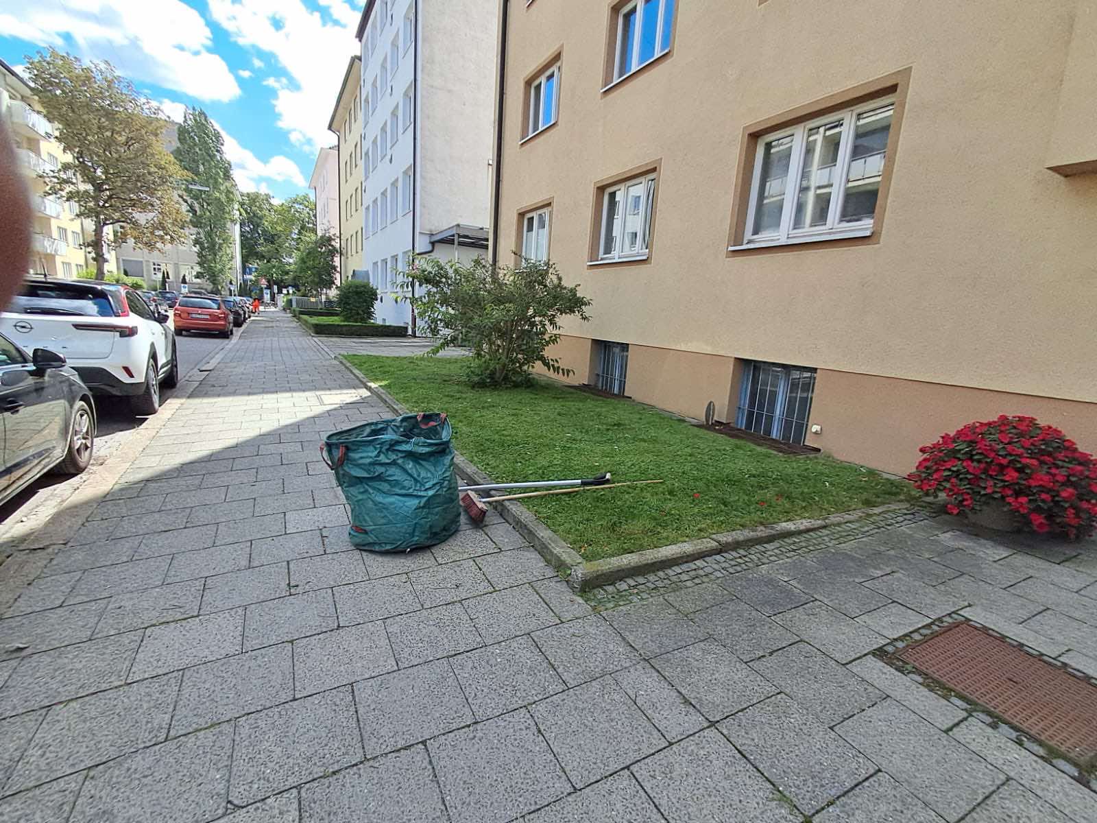 Rasenpflege und Laubentfernung vor einem Mehrfamilienhaus