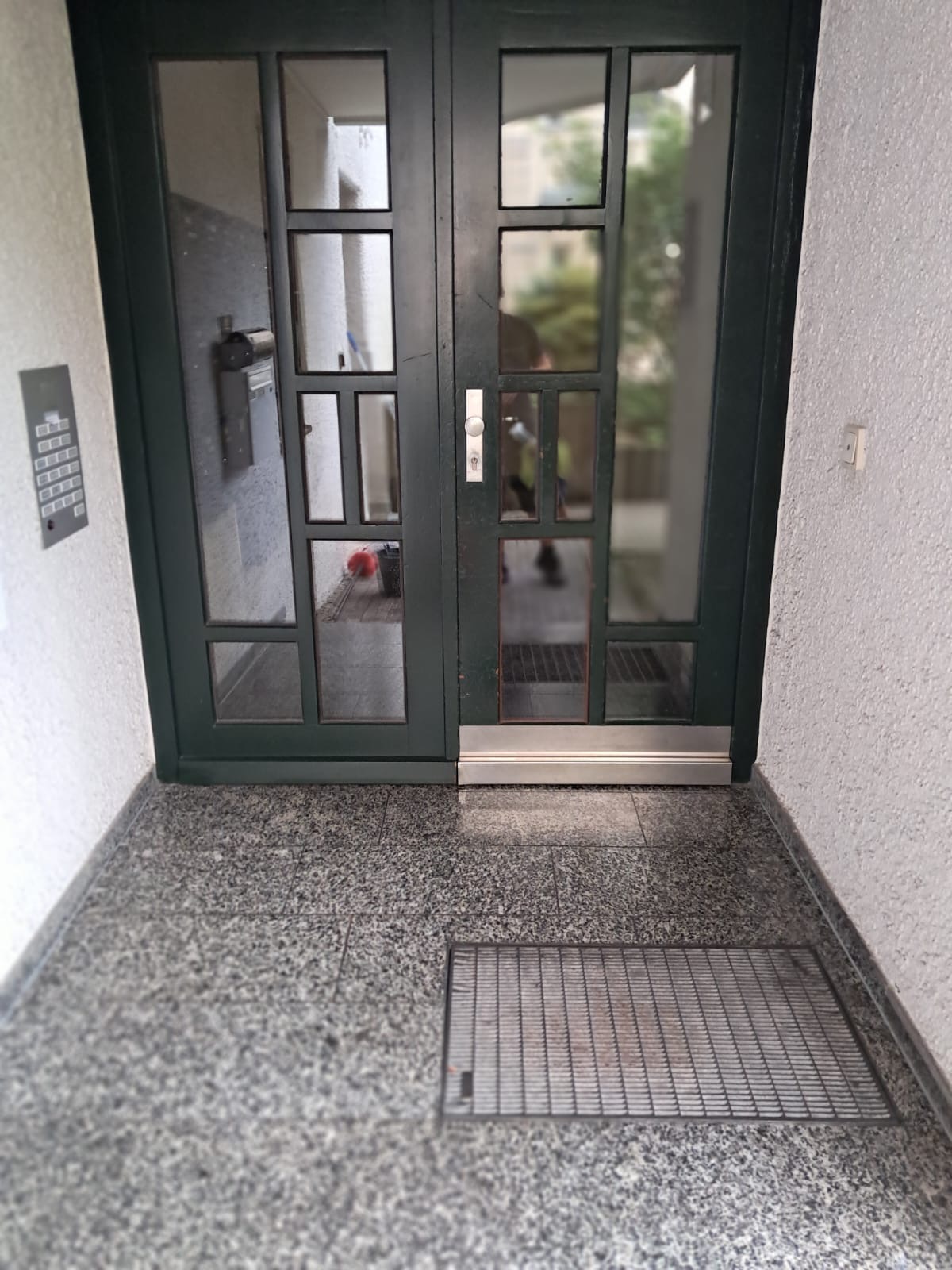 Gereinigter Hauseingang mit Glastür und sauberem Granitboden