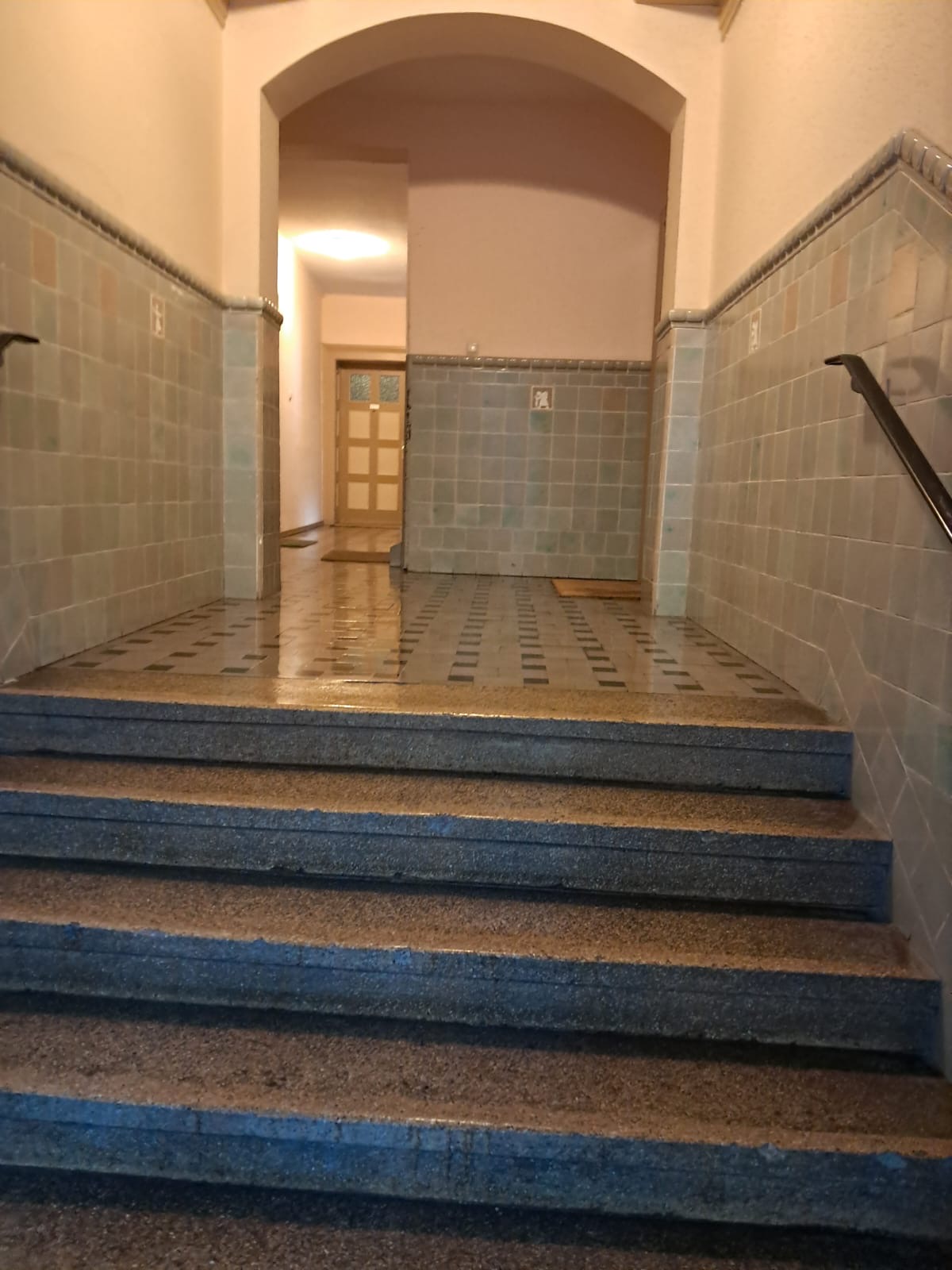 Gereinigter Eingangsbereich mit Fliesenwand und Treppenstufen