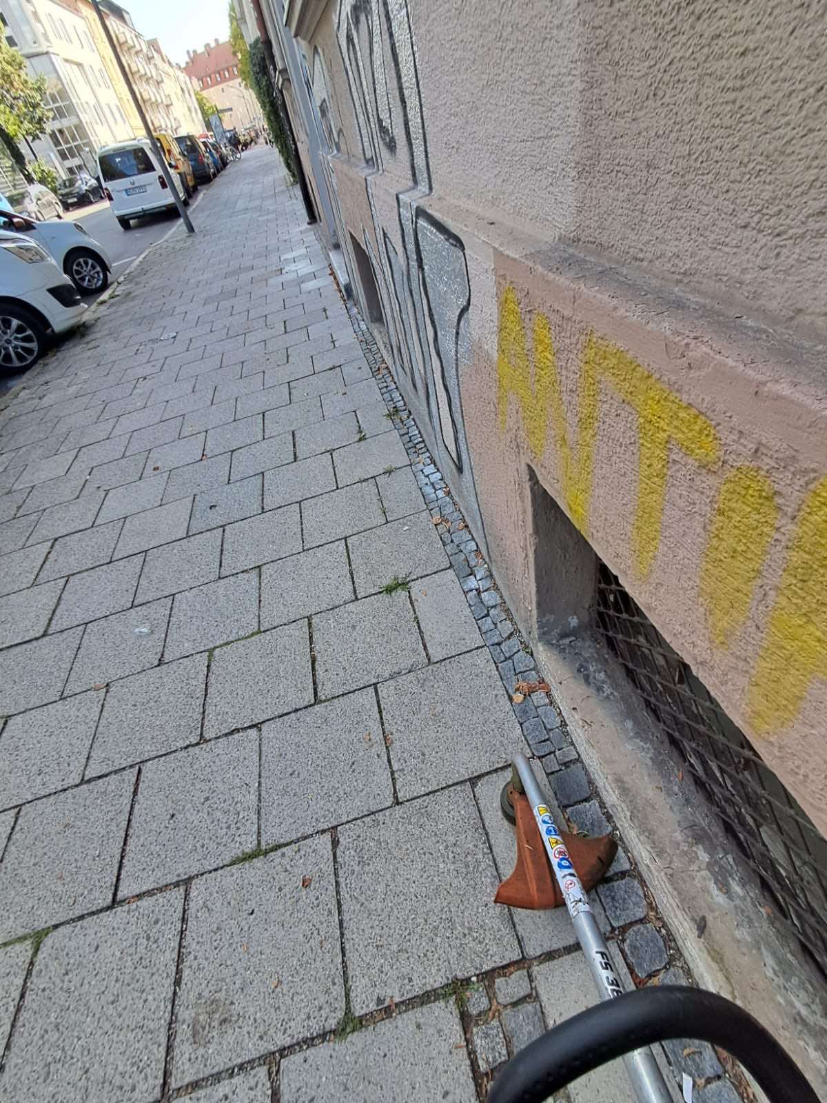 Freischneiden des Gehwegrands entlang einer Hausfassade in München
